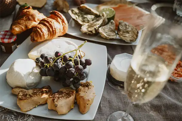 Picnic near the Seine in front of Eiffel tower. Fruits, french cheeses, shrimps, snacks, croissants, oysters, foie gras, delicacies, a bouquet of flowers and a bottle of expensive champagne.